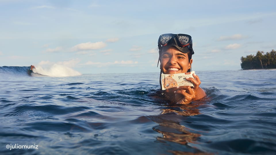 Girl holding dairy-free protein bar in the ocean