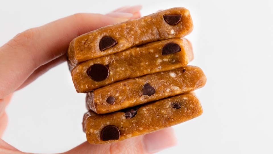 Hand holding a stack of GoMacro Salted Caramel + Chocolate Chips MacroBars