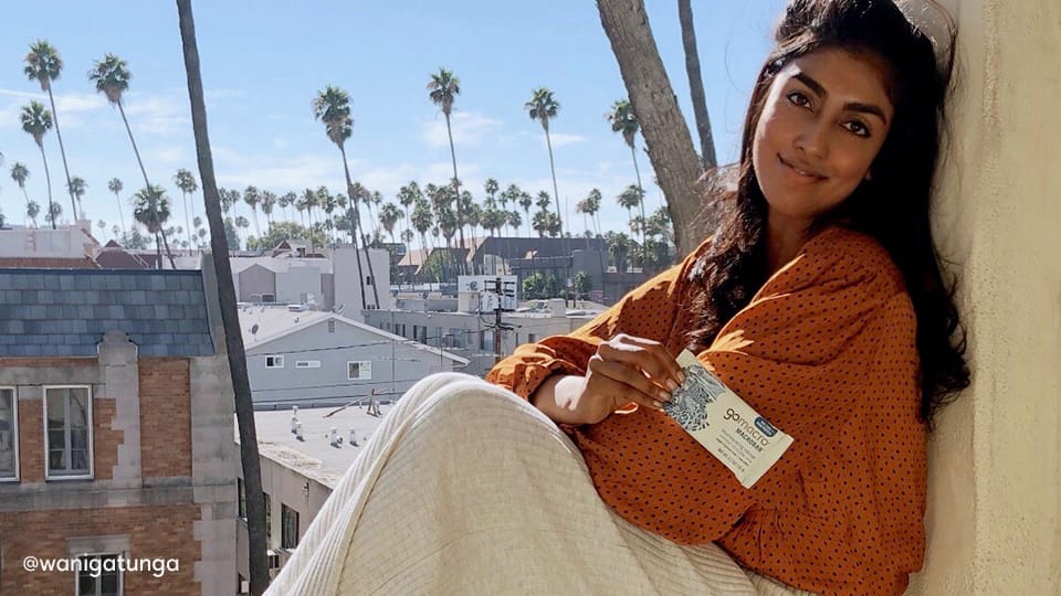 Woman sitting in window sill holding GoMacro MacroBar