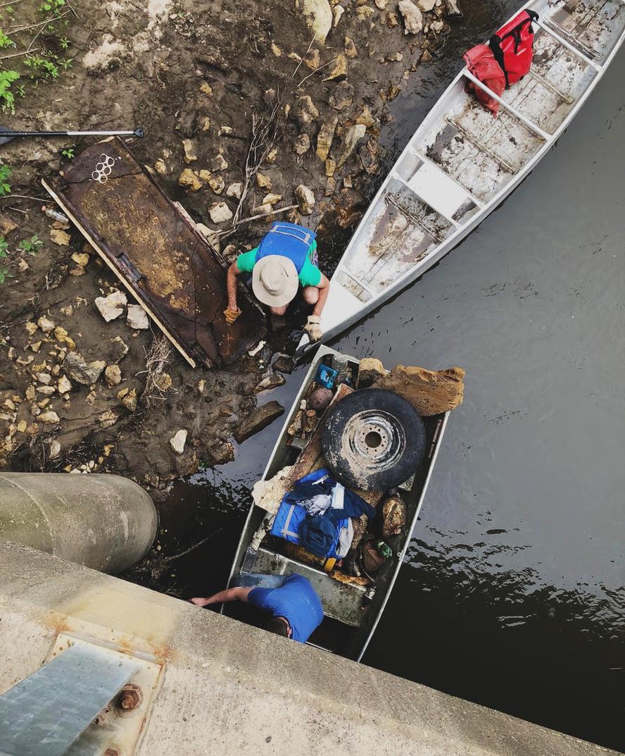 Man with boats cleaning up trash from Kickapoo river