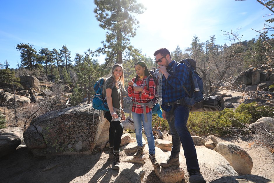 Three hikers holding GoMacro protein bars