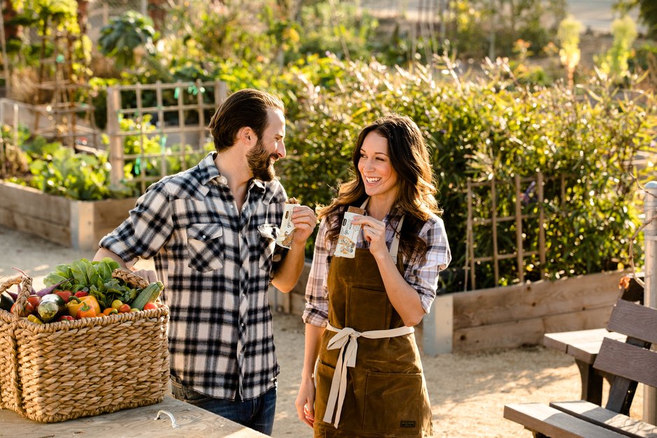 Man and woman in farm eating GoMacro protein bars