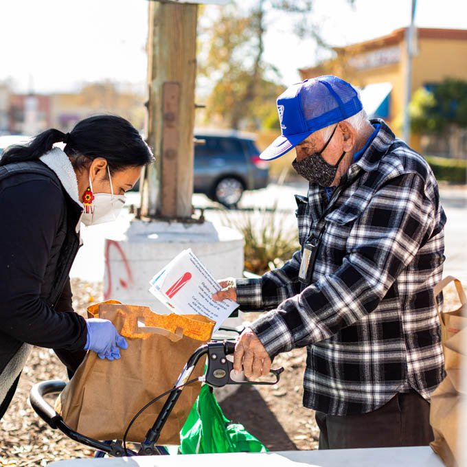 Woman handing a bag of groceries to man