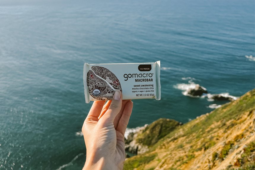 Protein bar held in front of ocean