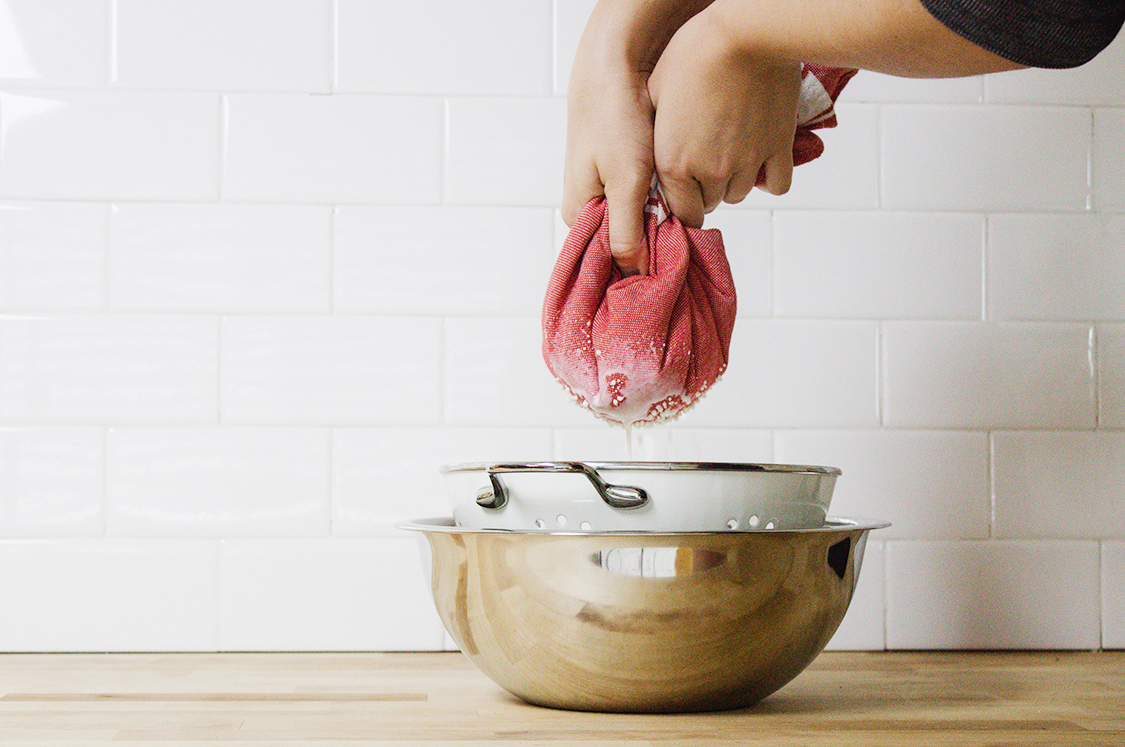 Homemade almond milk straining through cloth