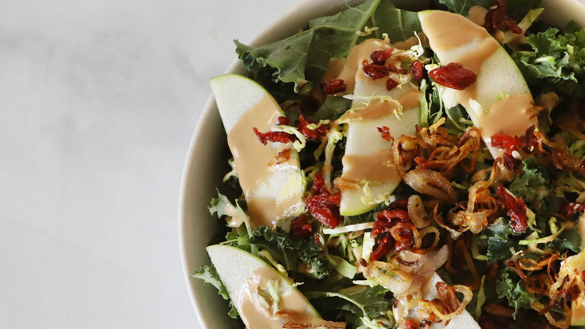 Kale salad topped with a maple-almond vinaigrette and green apples