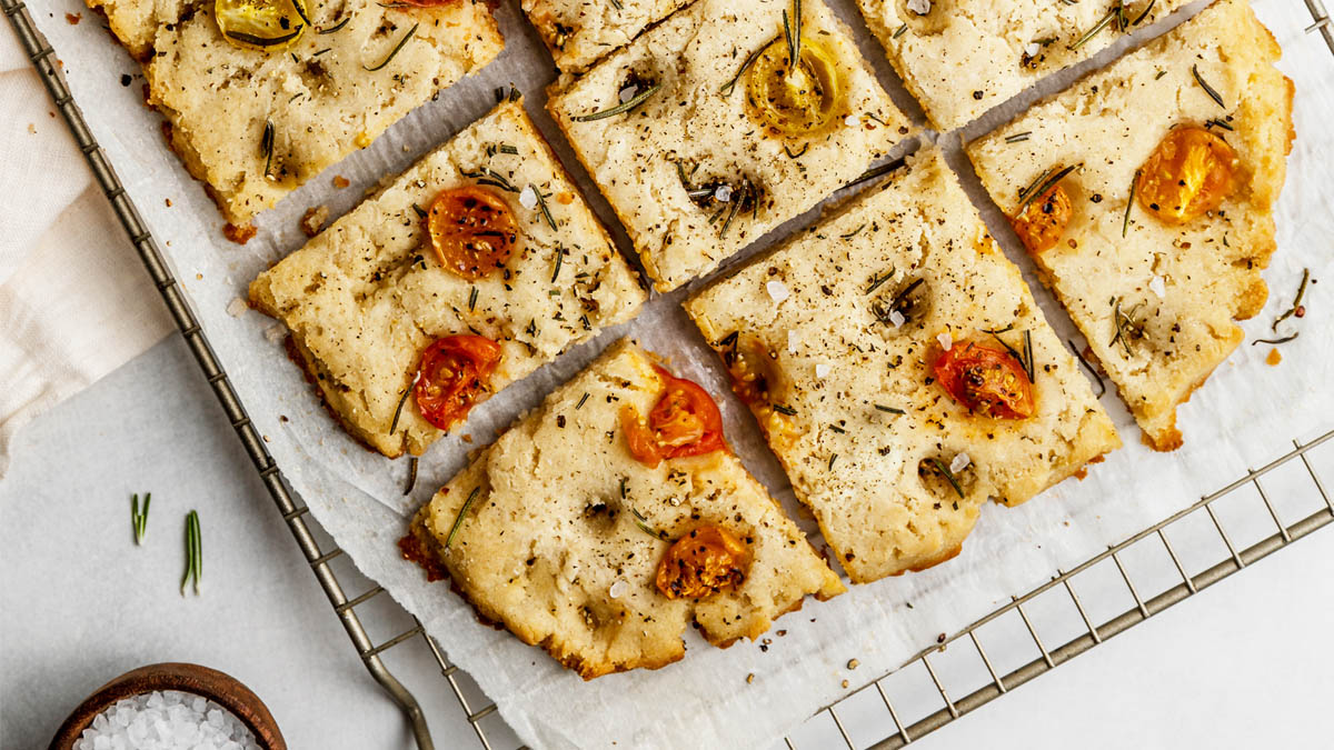 A pan of focaccia topped with rosemary and tomato