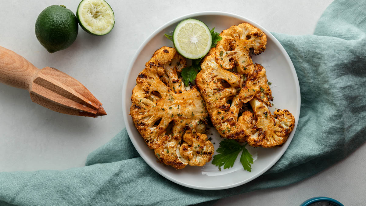 A plate of grilled cauliflower steaks topped with lime