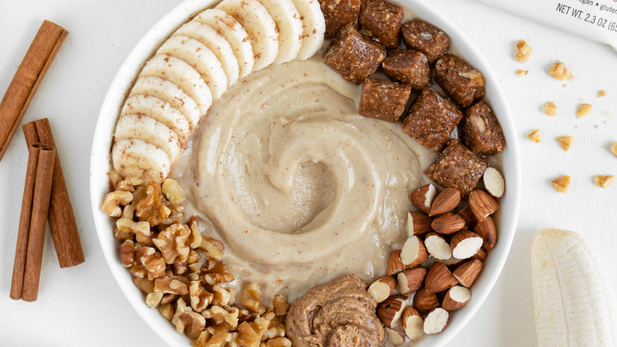 Smoothie bowl topped with bananas, nuts, and a GoMacro protein bar