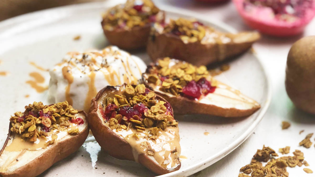 Baked pears on a plate with peanut butter and granola