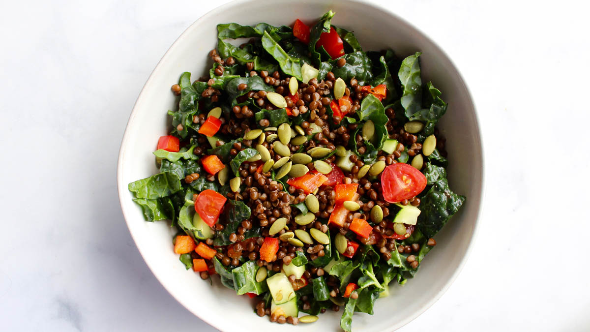 Kale and lentil salad topped cucumbers and tomatoes