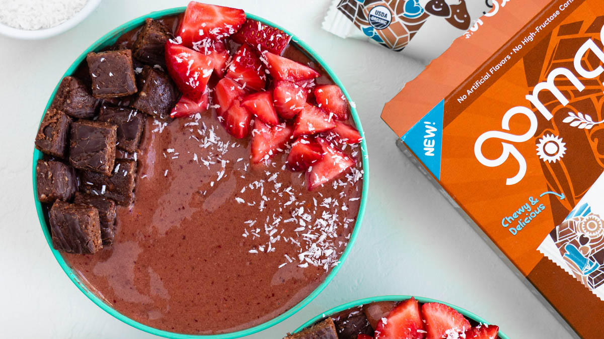 Chocolate smoothie bowl topped with strawberry and a GoMacro protein bar