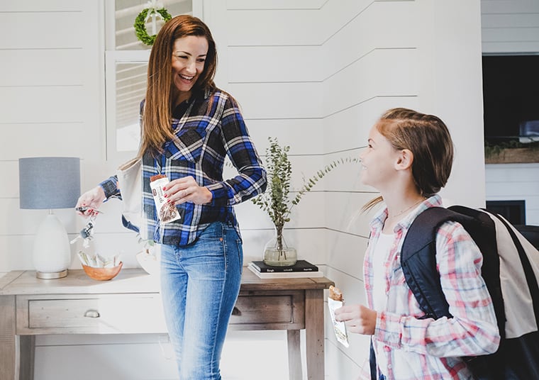 Woman and child heading out the door with GoMacro protein bars in hand