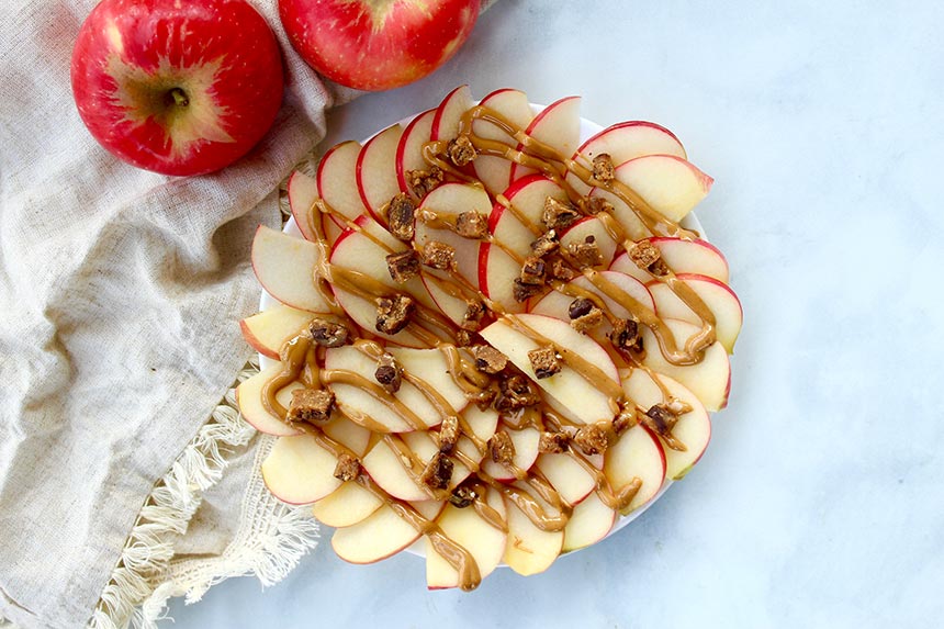 Sliced apples with peanut butter drizzle and bits of GoMacro protein bars