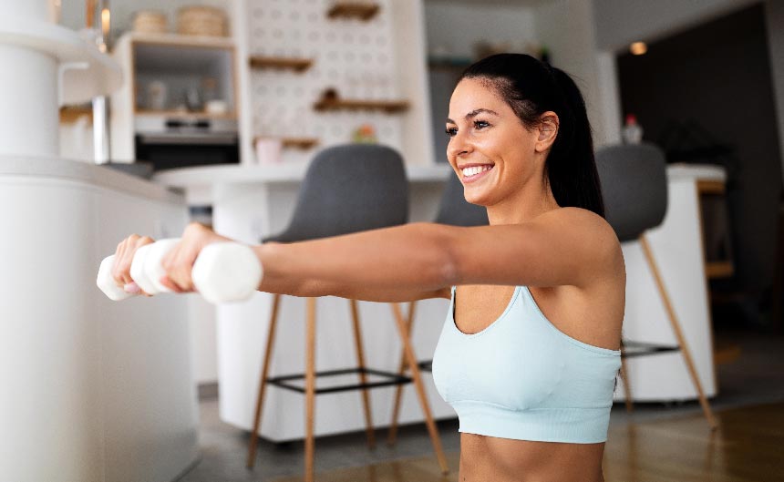 Woman holding weights working out in living room