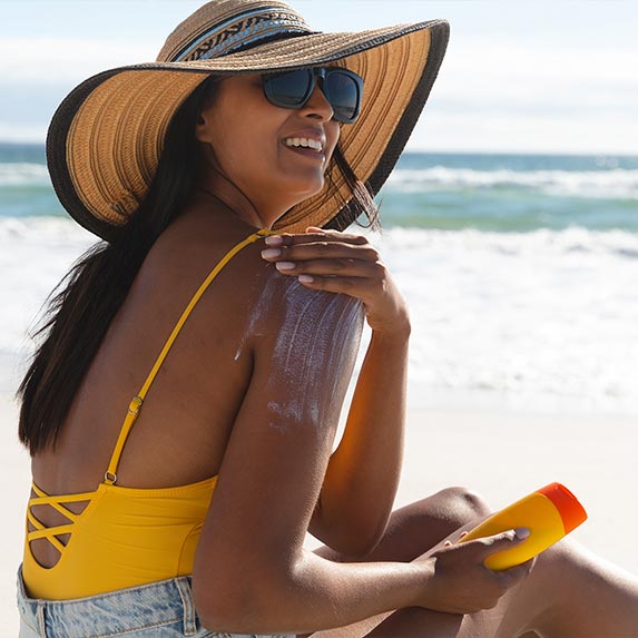 Woman putting on sunscreen at the beach