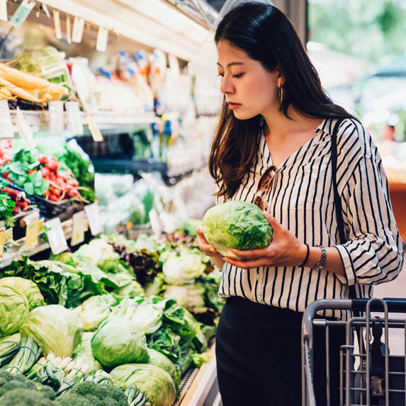 Woman in grocery store holding a cabbage