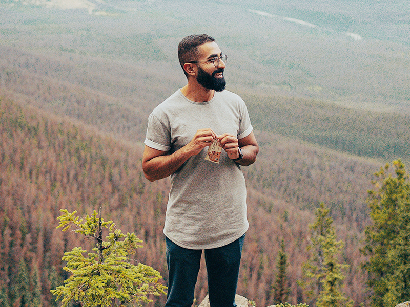 GoMacro Ambassador standing in nature holding a GoMacro MacroBar