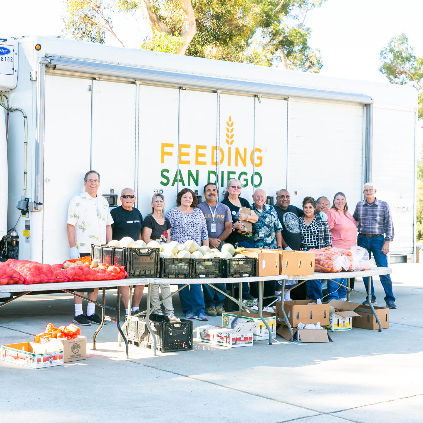 Feeding San Diego volunteers behind a tables filled with food